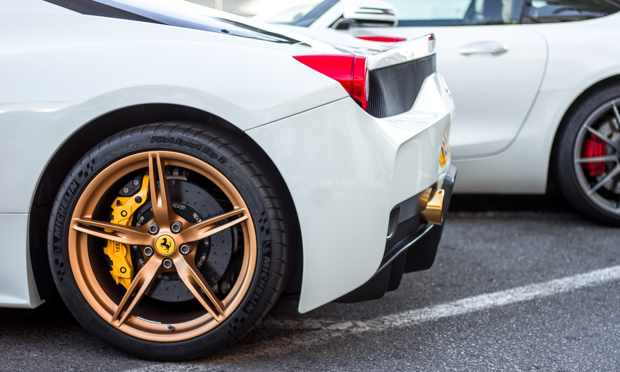 This is a photo of the back side of a white car with gold wheels.